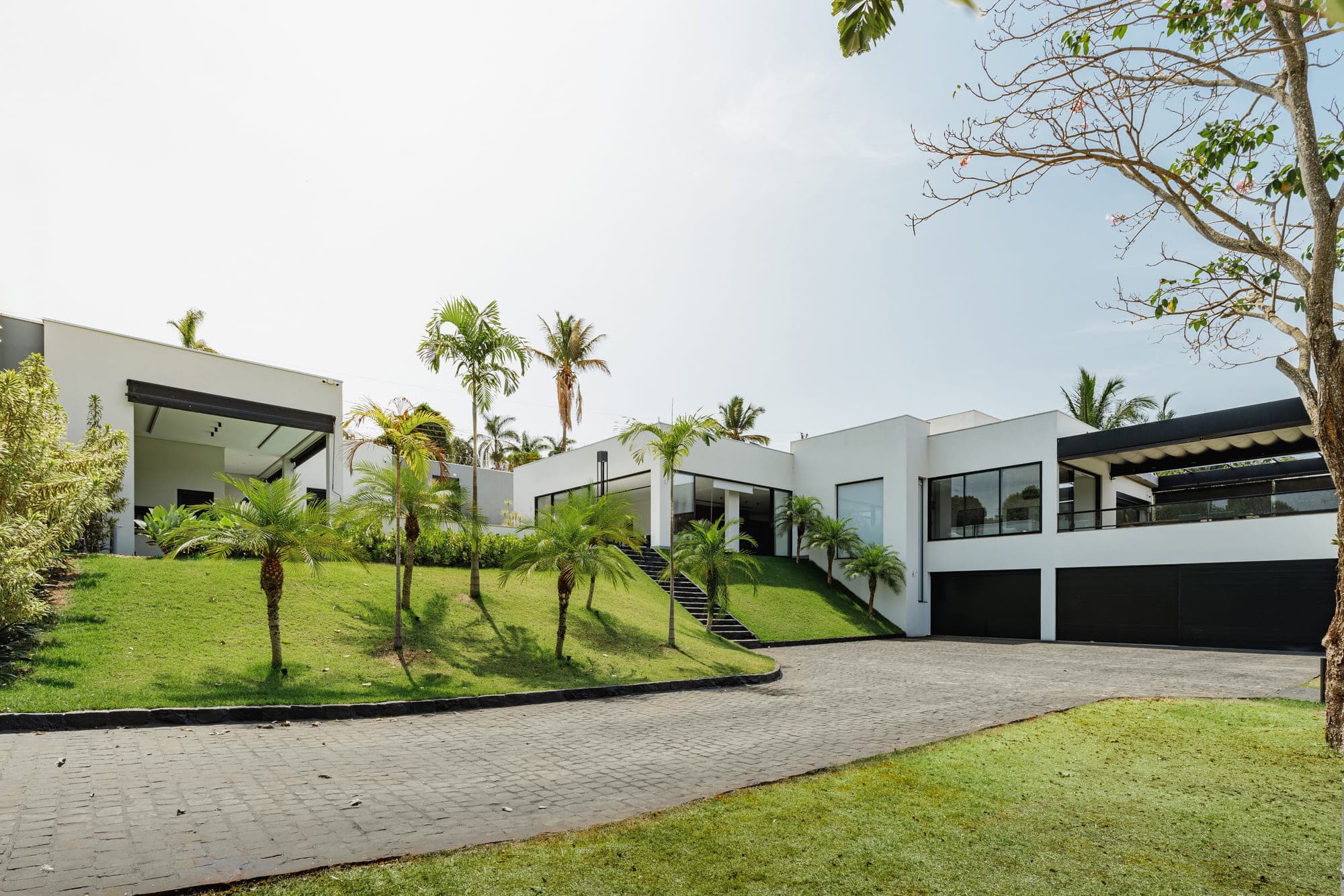 Vista aérea de casas de condomínio com jardins, piscina e palmeiras