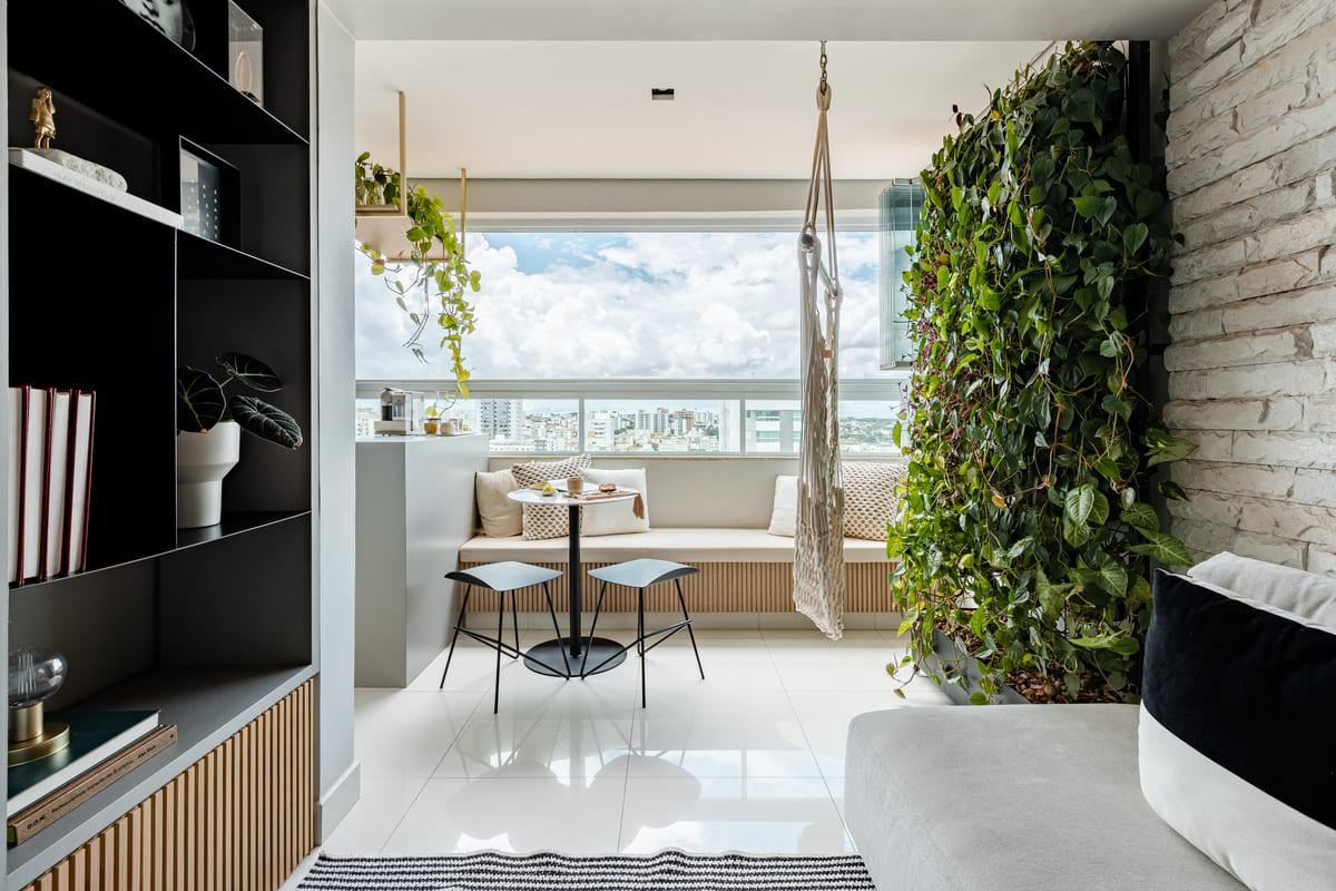 Varanda de apartamento com jardim vertical, mesa de café e vista para a cidade